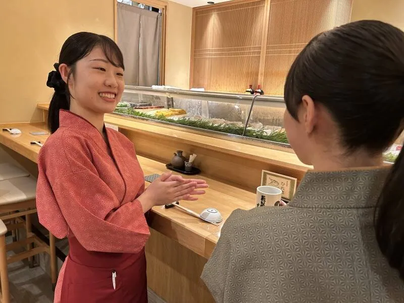 カウンター席で、先輩スタッフが接客を教えている様子